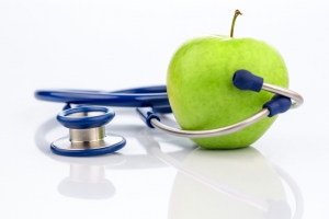 Ein Apfel und ein Stethoskop bei einem Arzt. Symbolfoto für gesunde und vitaminreiche Ernährung.